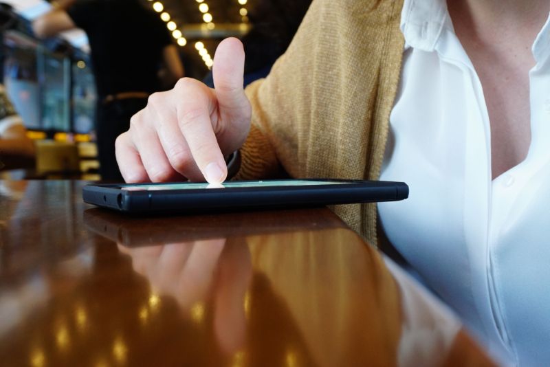 woman scrolling through her phone in a coffee shop